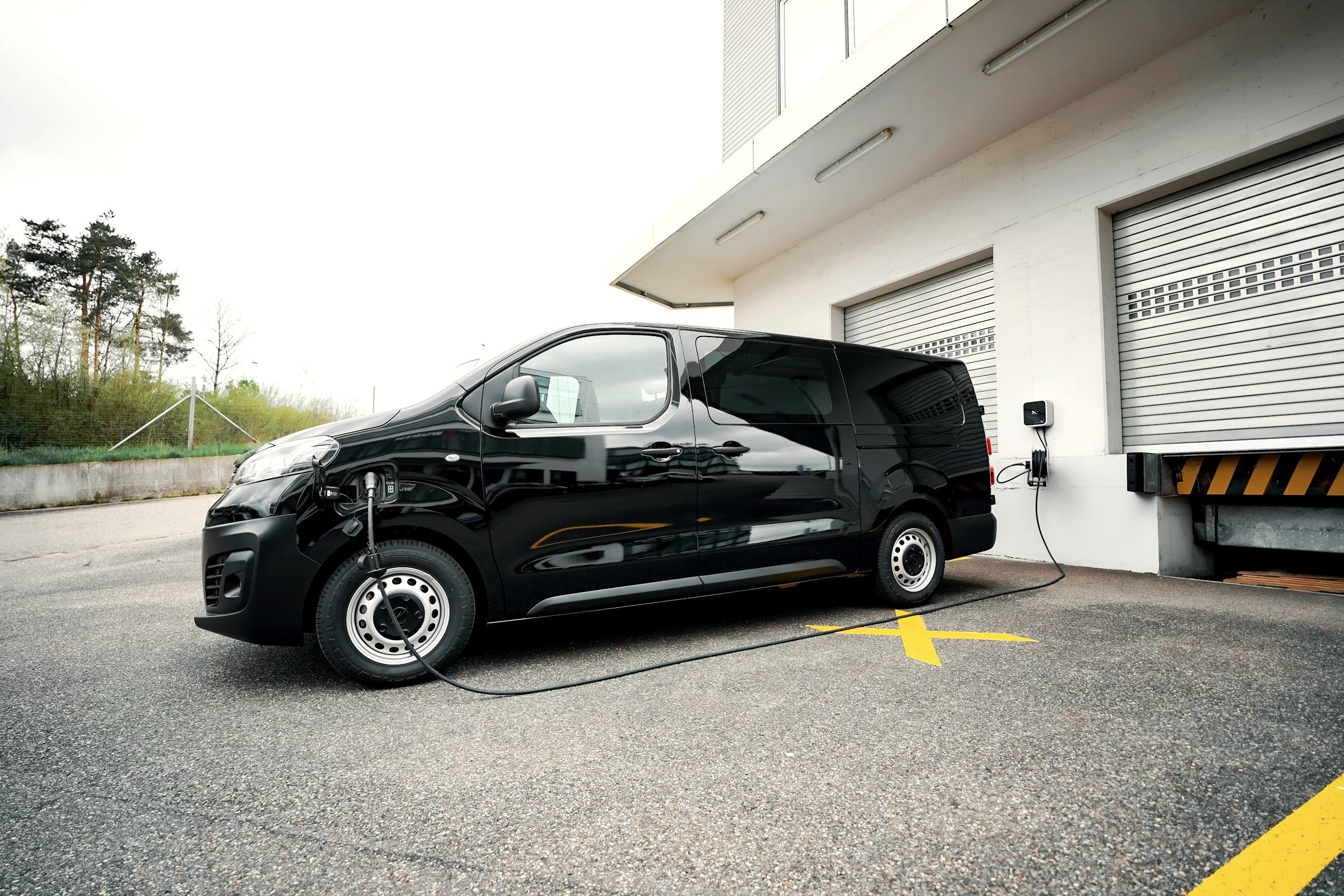 Elektrischer Transporter lädt am Firmengebäude