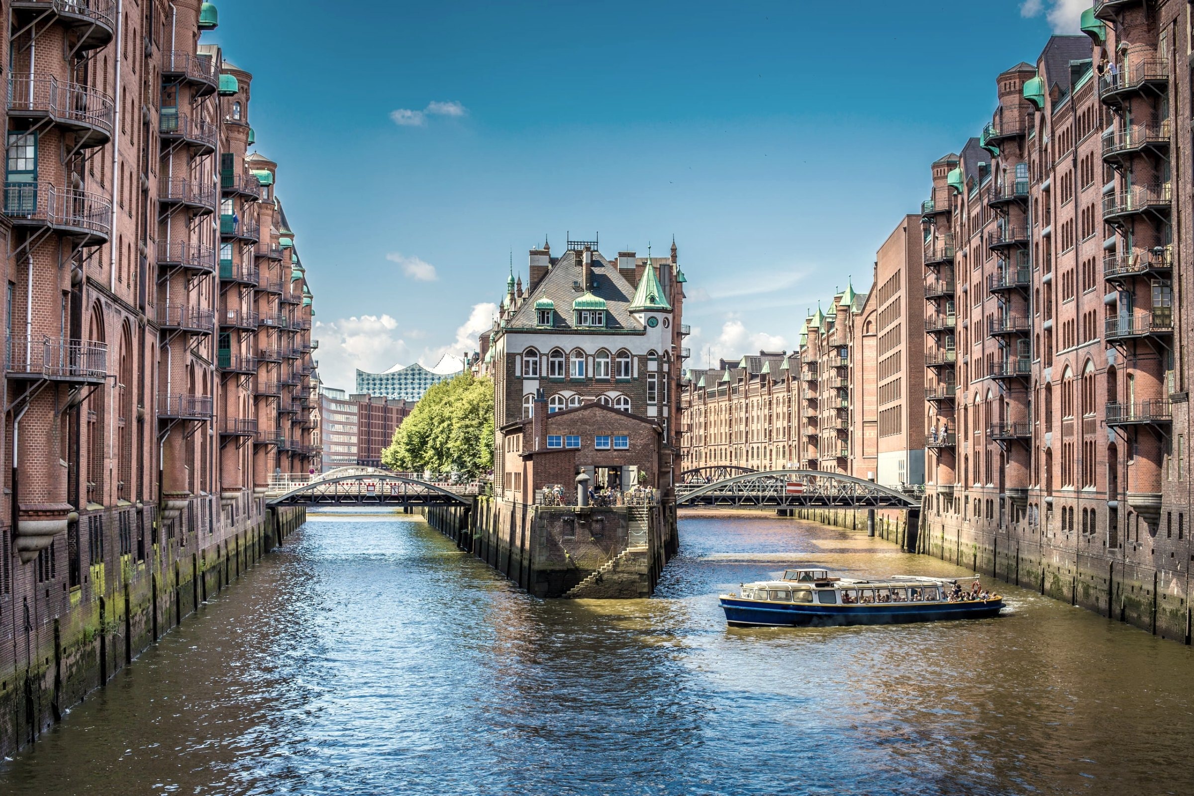 Speicherstadt Hamburg mit Fleet, historischen Backsteinbauten und Ausflugsboot bei Sonnenschein