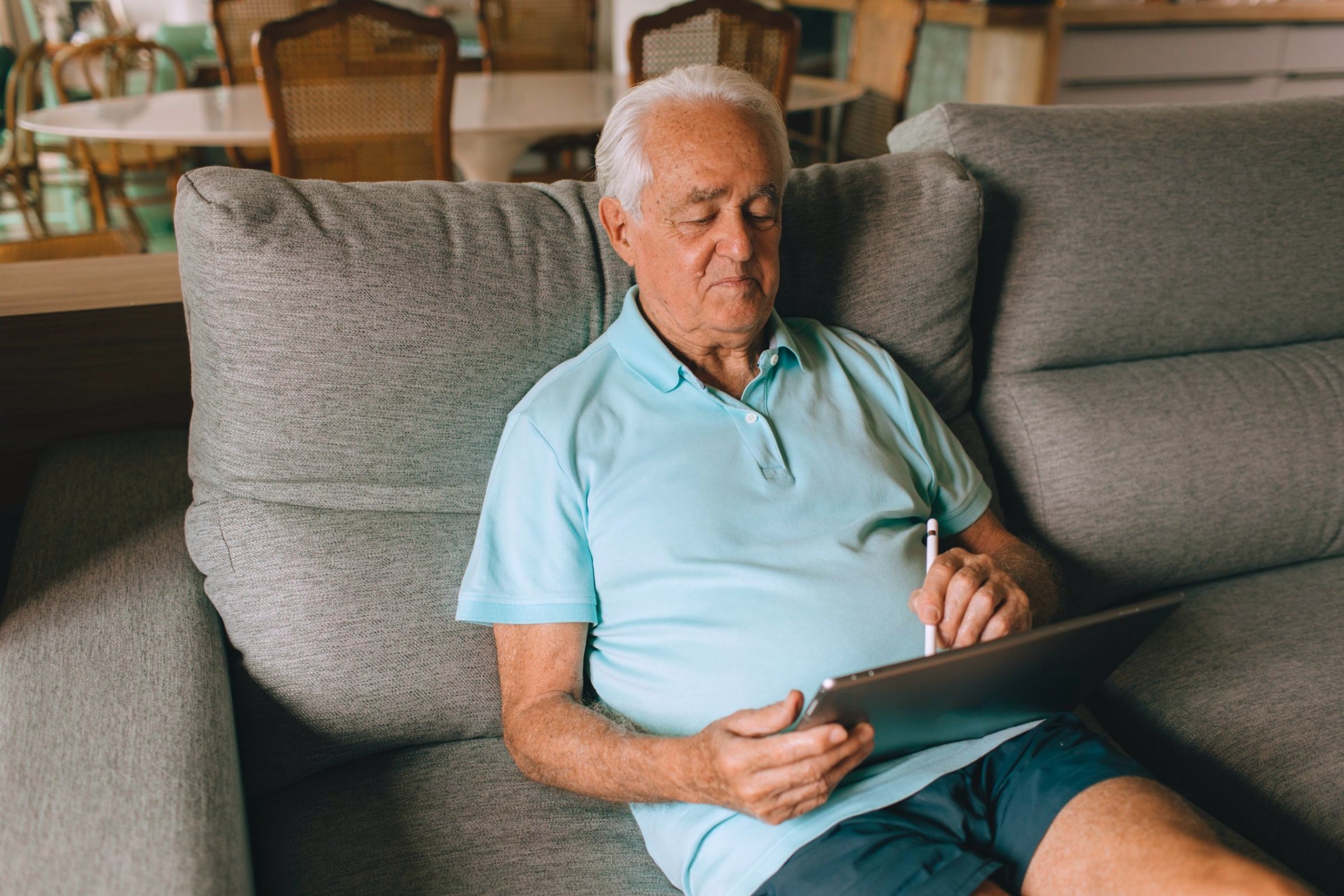 Mann liest auf dem Sofa auf dem Tablet