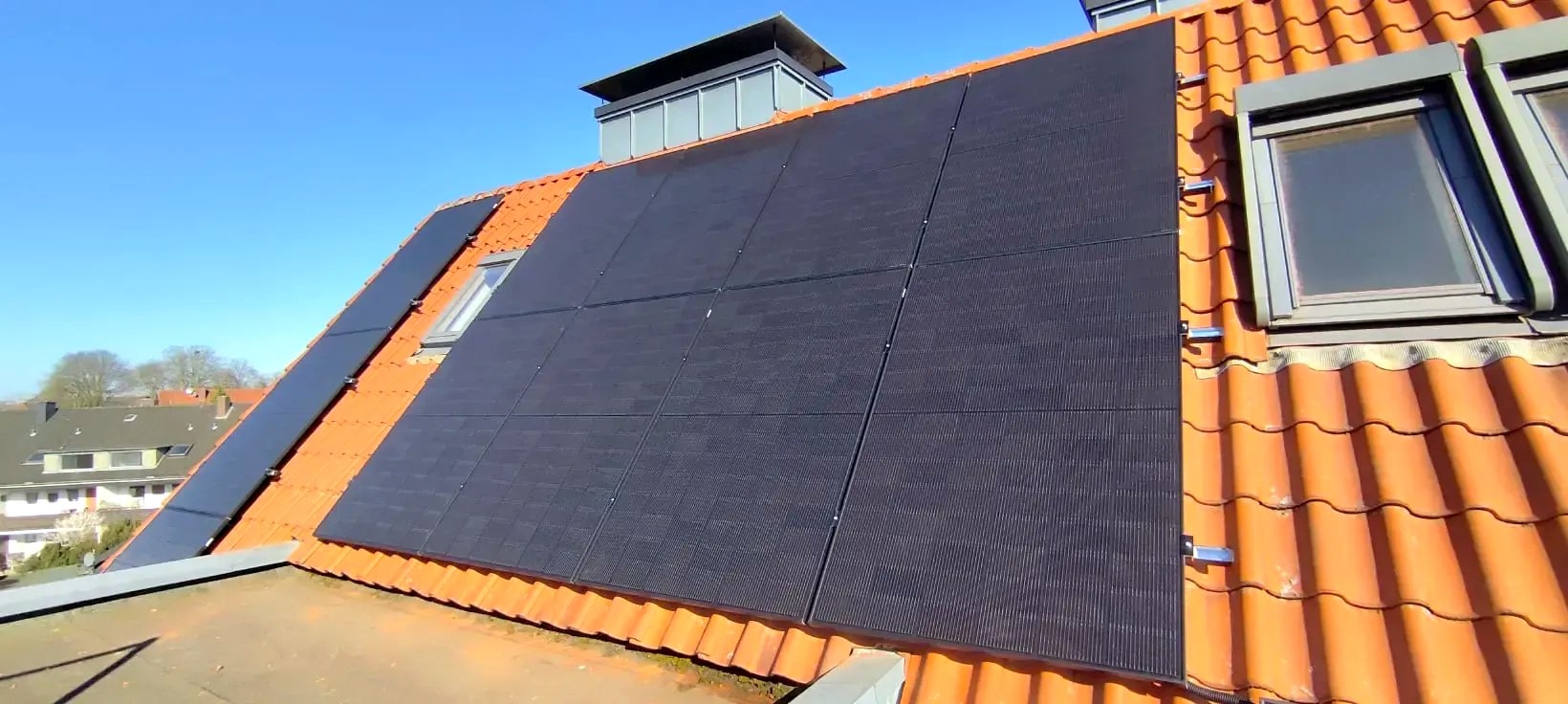 Schwarze Solarmodule auf einem roten Ziegeldach