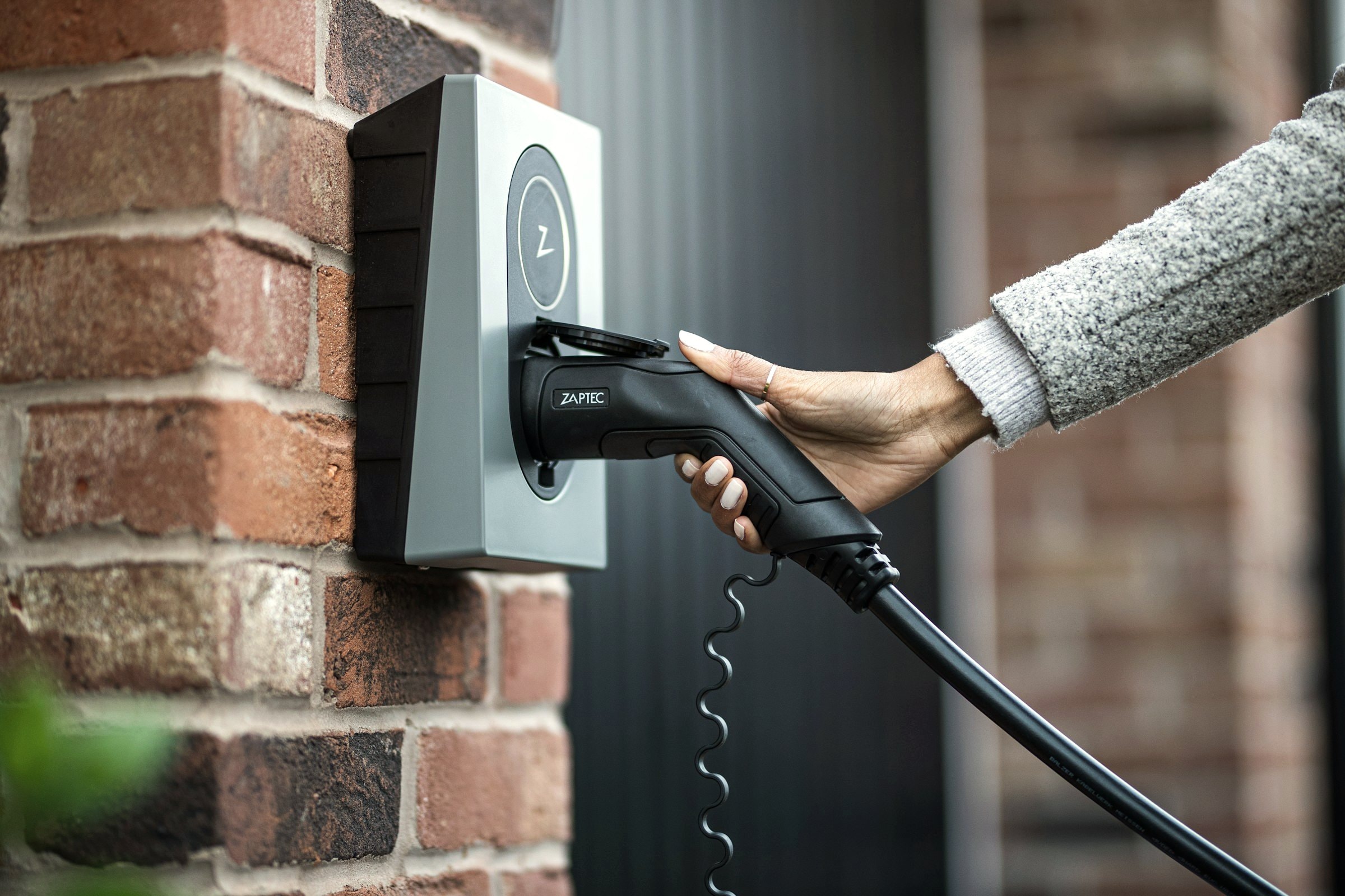 Ladekabel wird in eine Wallbox an einer Klinkerwand gesteckt
