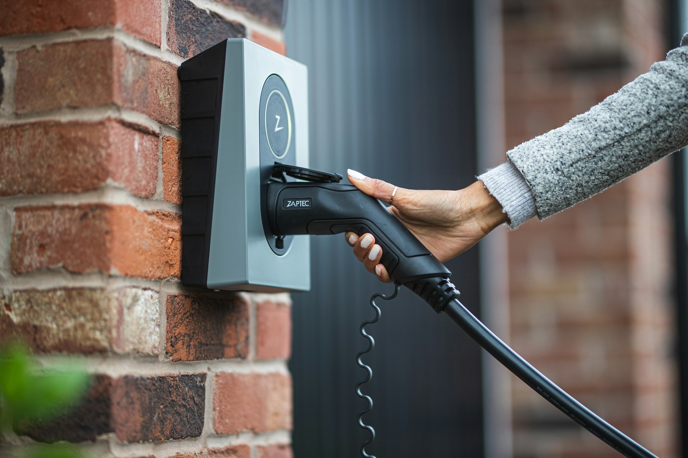 Ladekabel wird in eine Wallbox an einer Klinkerwand gesteckt