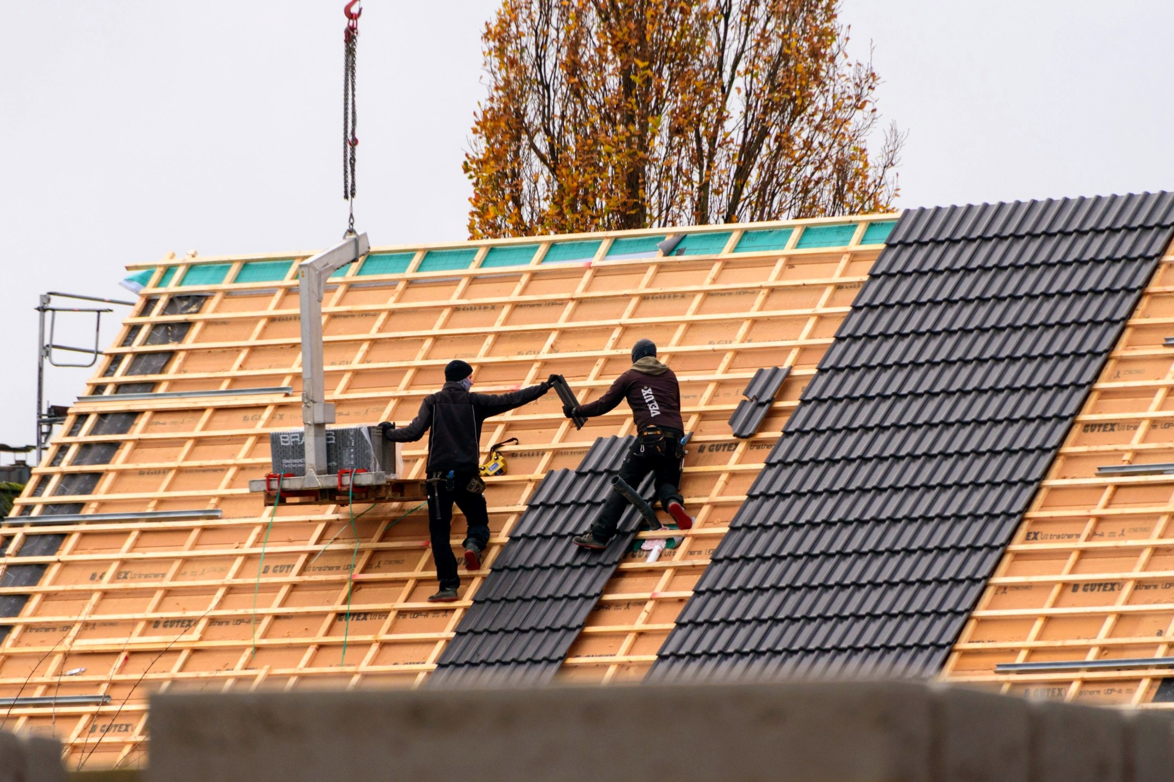 Handwerker montieren schwarze Indach-Solarmodule auf einem Neubau