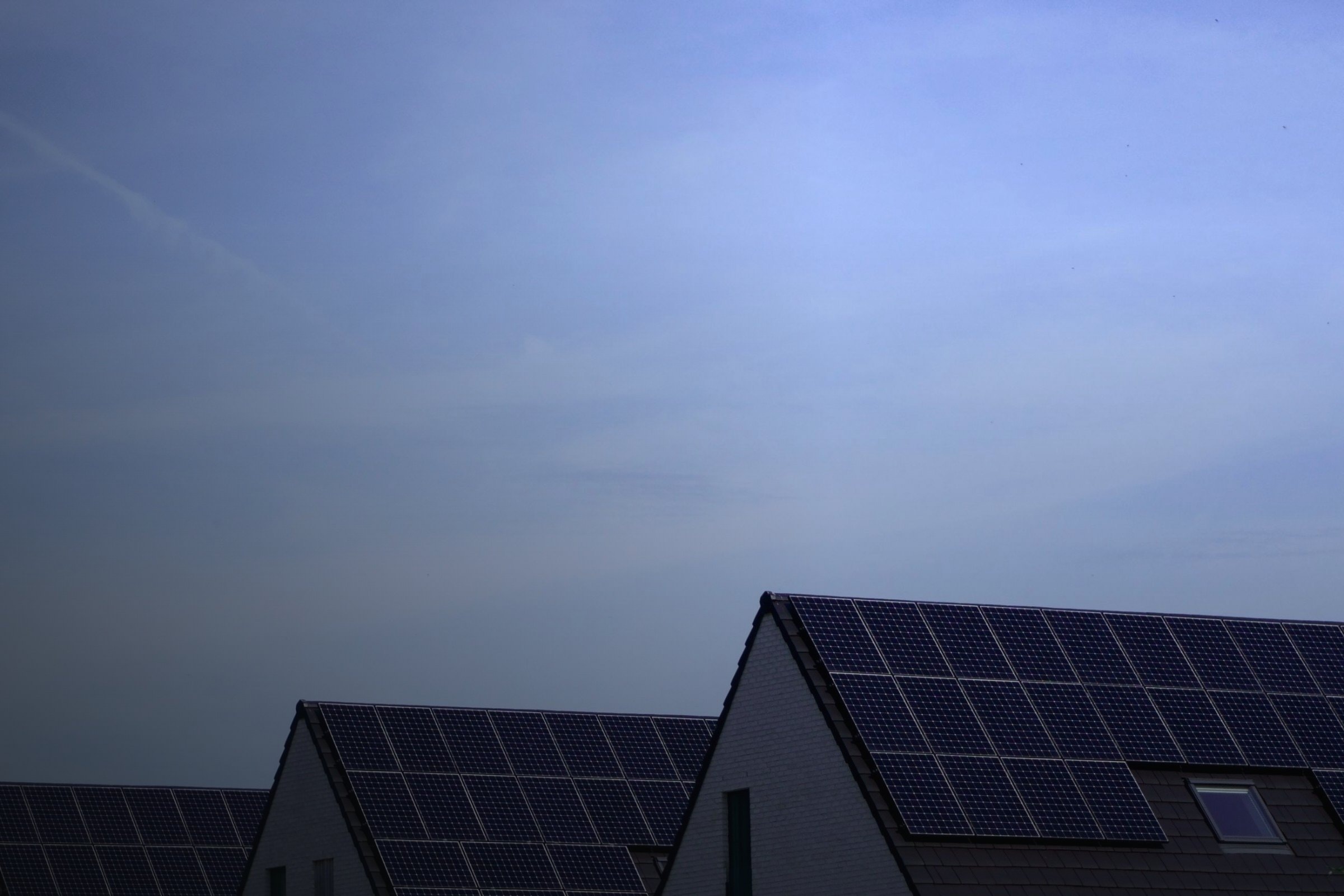Einfamilienhäuser mit schwarzen Solardächern unter blauem Himmel