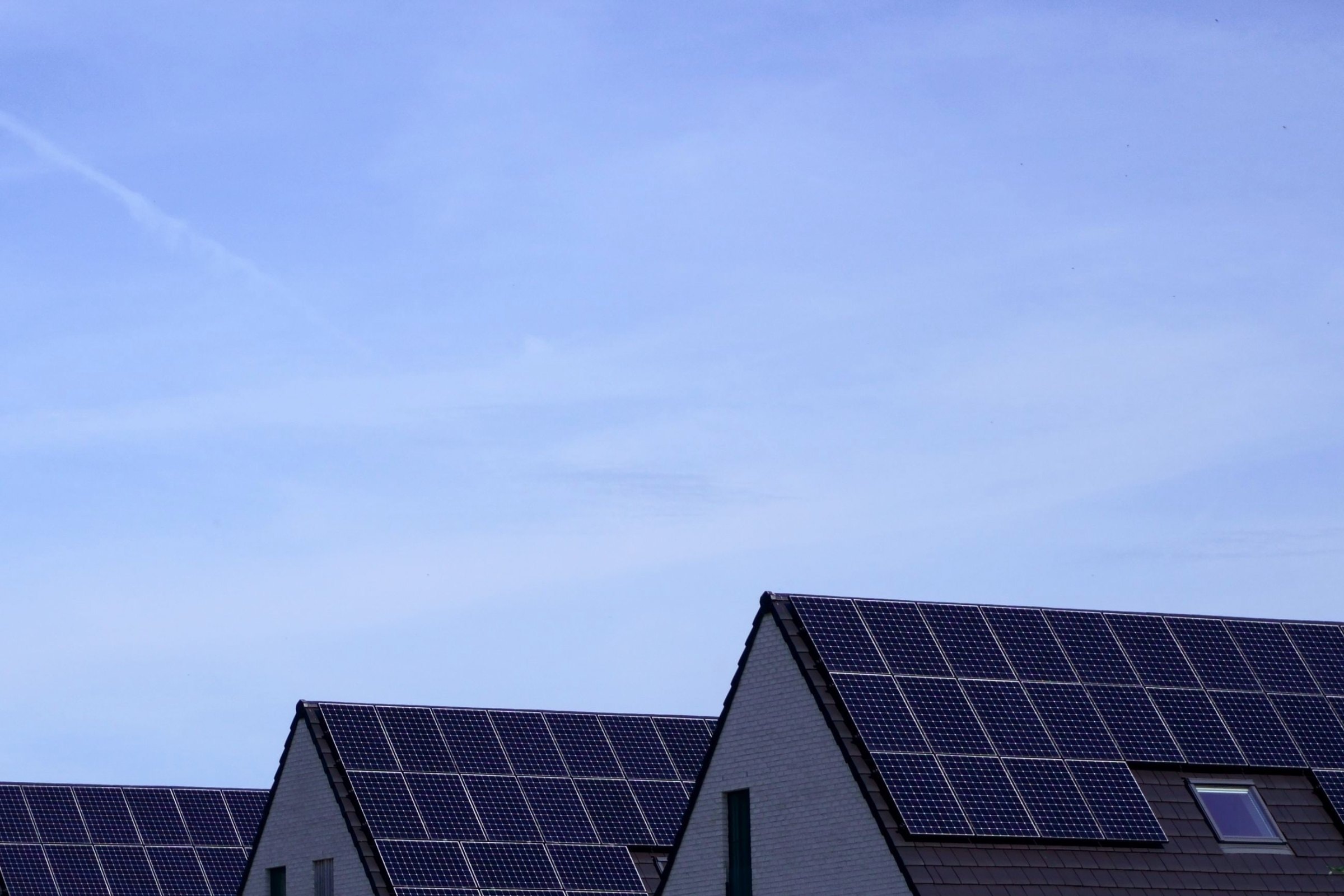 Einfamilienhäuser mit schwarzen Solardächern unter blauem Himmel