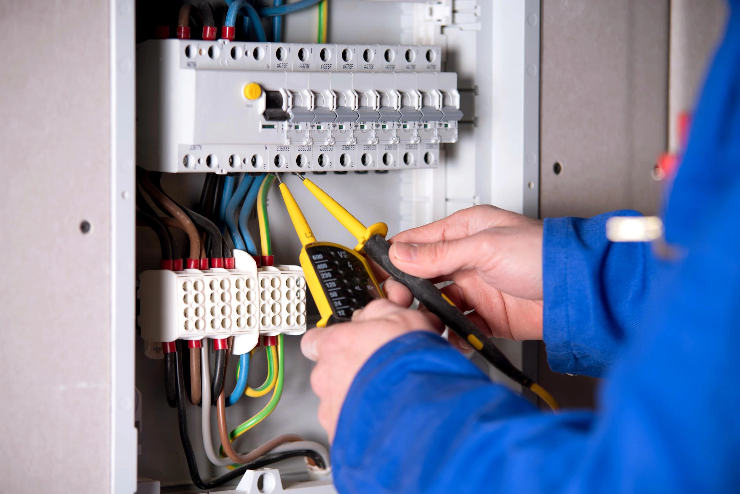 Elektriker prüft mit Messgerät die Verkabelung im Sicherungskasten bei der Elektroinstallation