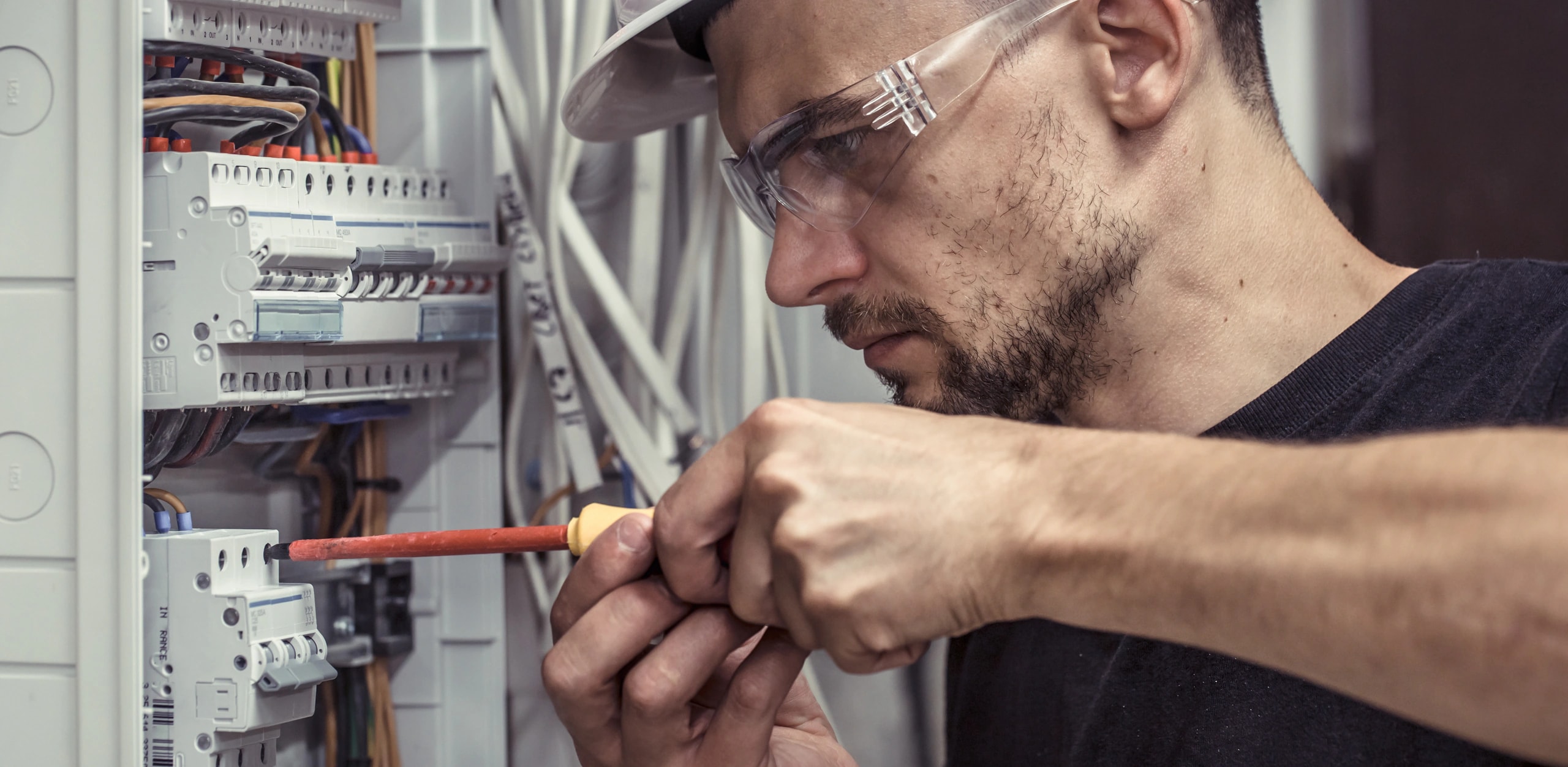 Elektriker installiert Sicherungskasten und verkabelt Verteiler für Photovoltaik und Ladeinfrastruktur