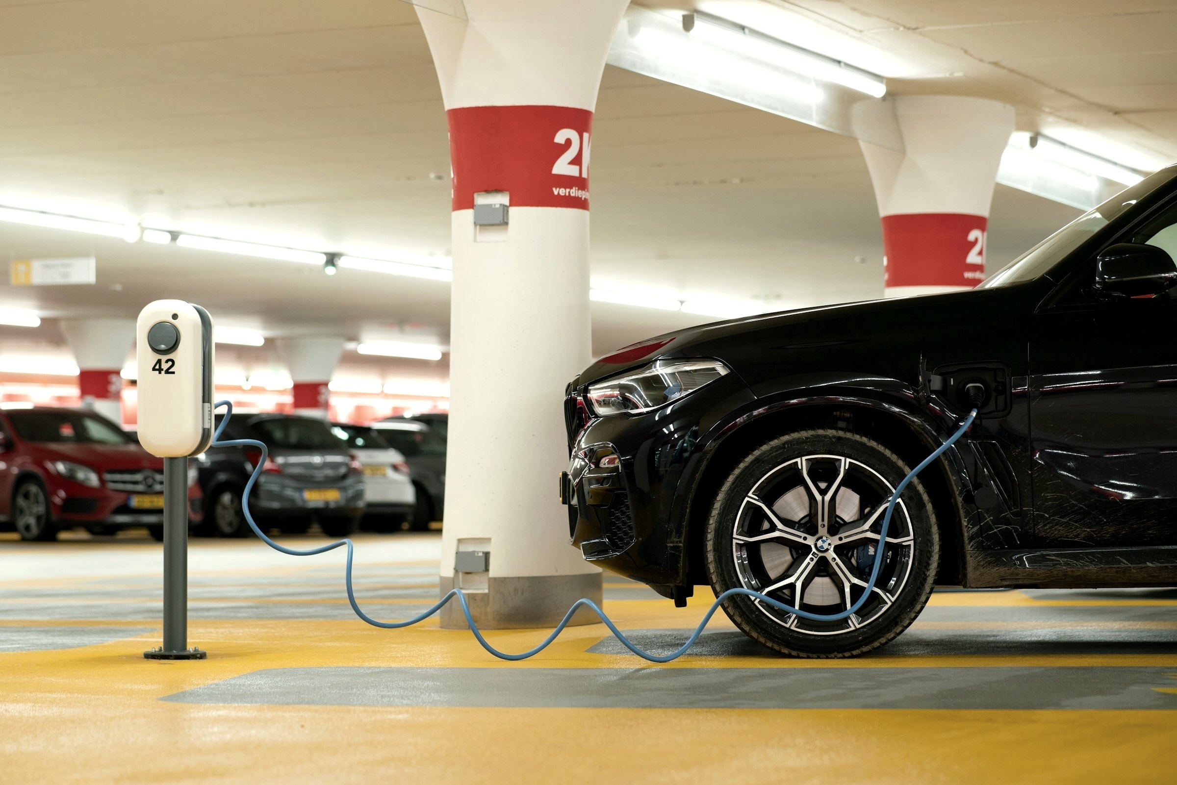 Elektroauto lädt an einem Ladepunkt in einer Tiefgarage, Ladeinfrastruktur für Wohnanlagen und Unternehmen