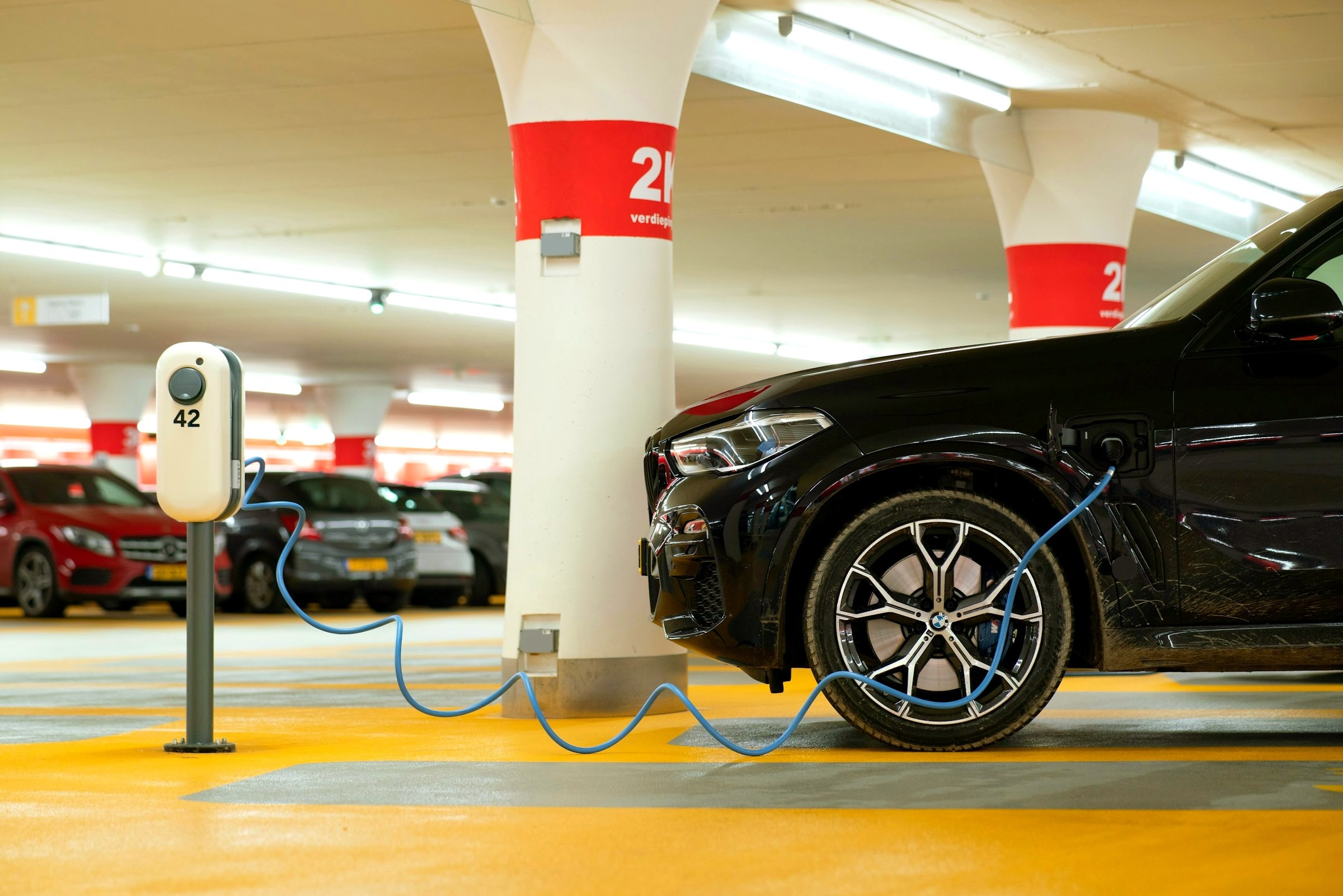 Elektroauto lädt an einem Ladepunkt in einer Tiefgarage, Ladeinfrastruktur für Wohnanlagen und Unternehmen