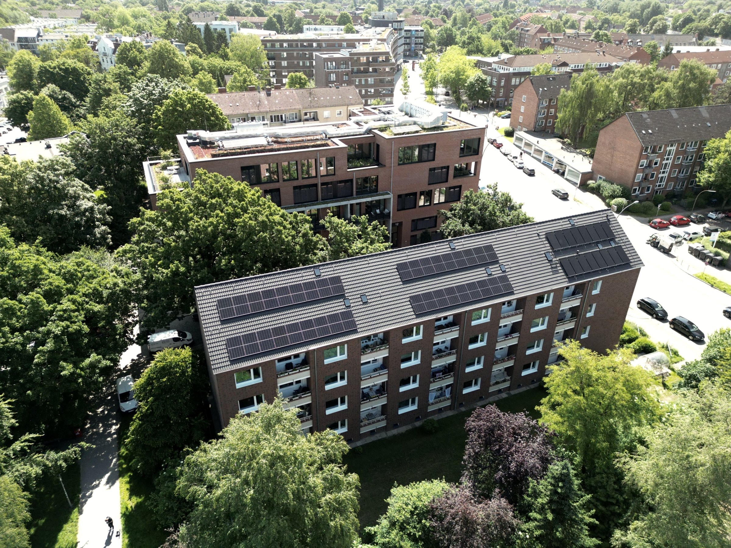 Luftaufnahme eines Mehrfamilienhauses mit Photovoltaikanlage auf dem Dach in der Stadt