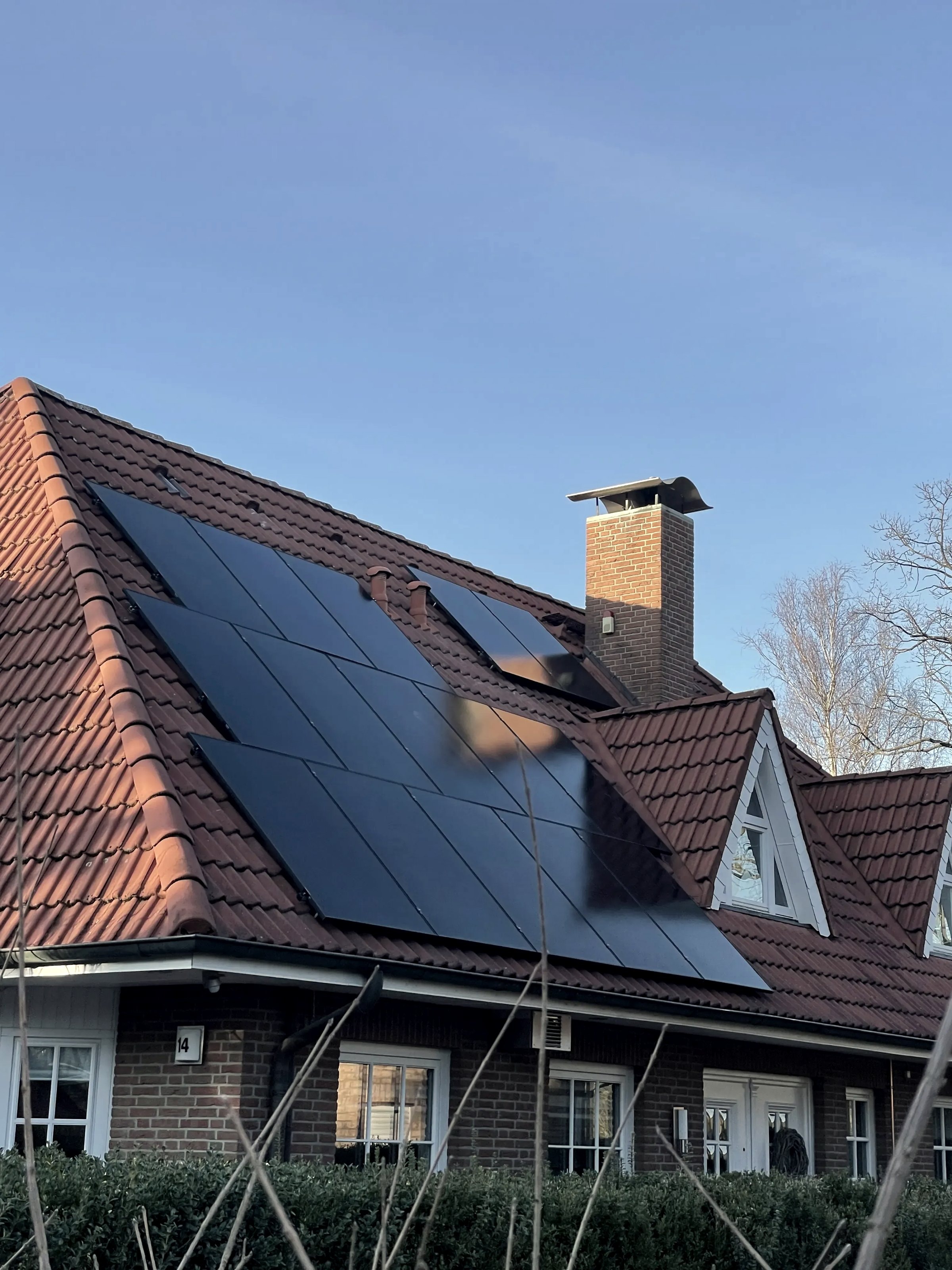 Photovoltaikanlage mit schwarzen Solarmodulen auf dem Ziegeldach eines Einfamilienhauses.