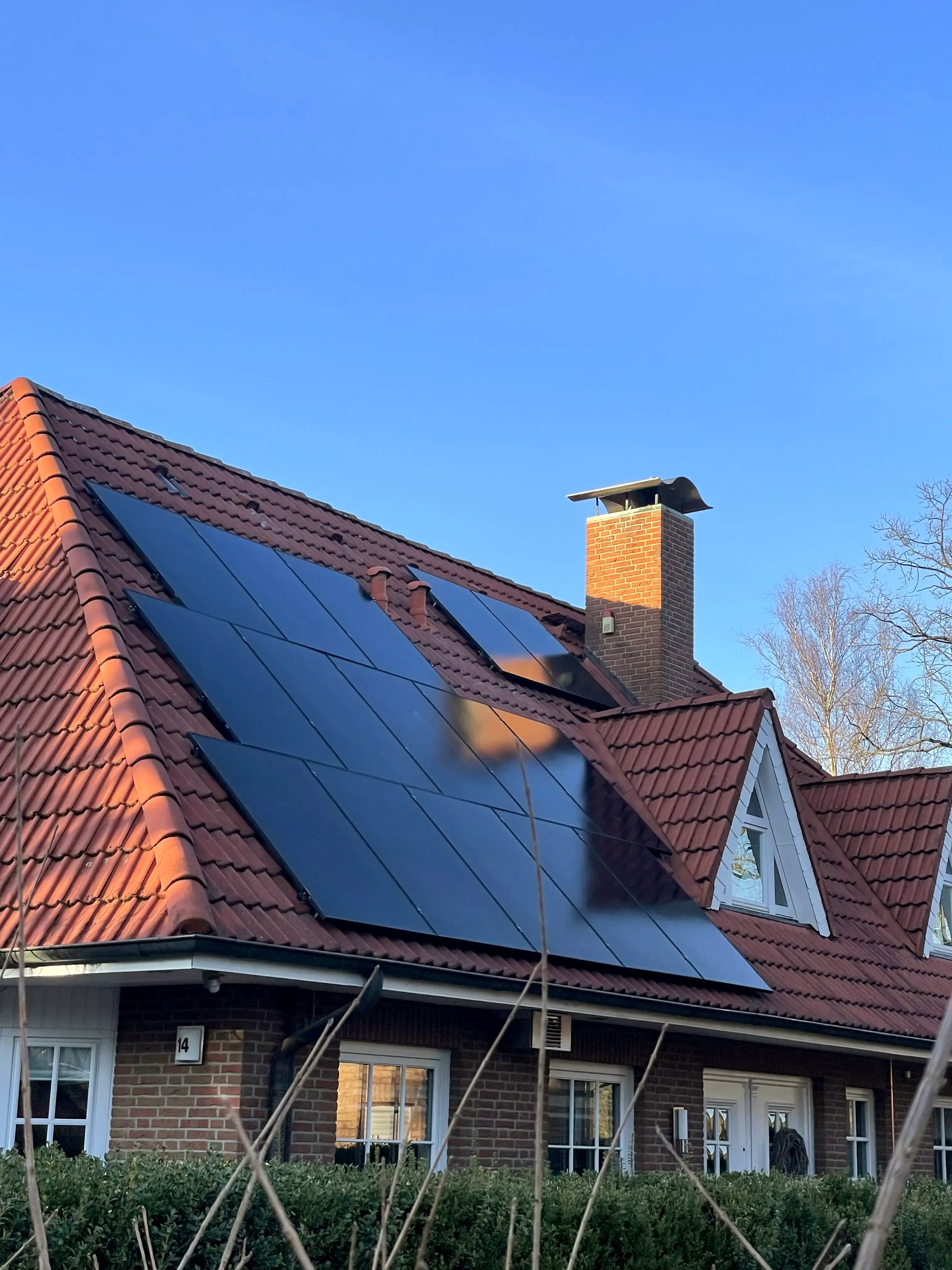 Photovoltaikanlage mit schwarzen Solarmodulen auf dem Ziegeldach eines Einfamilienhauses.