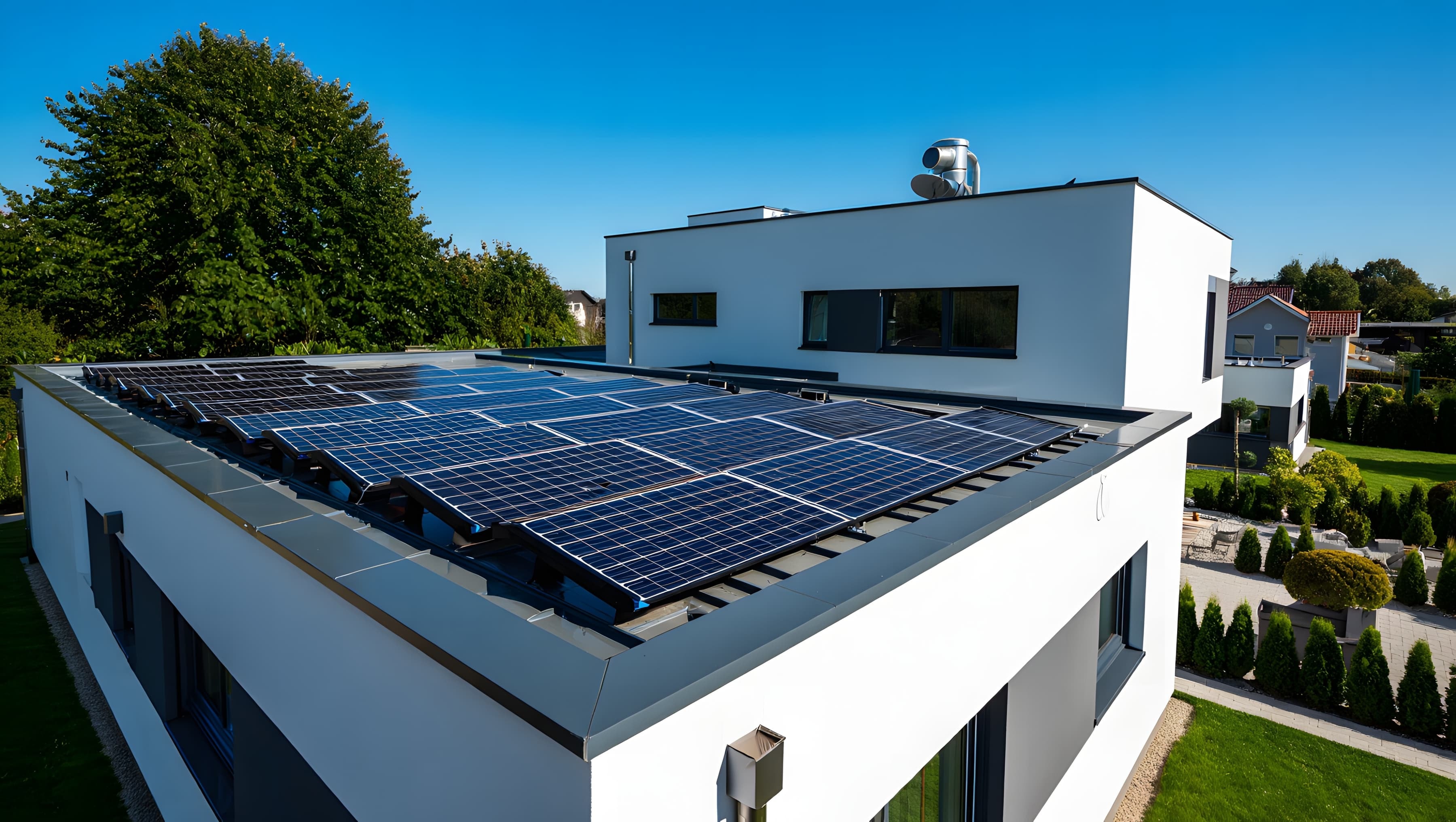 Photovoltaikanlage auf Flachdach eines modernen Einfamilienhauses unter blauem Himmel