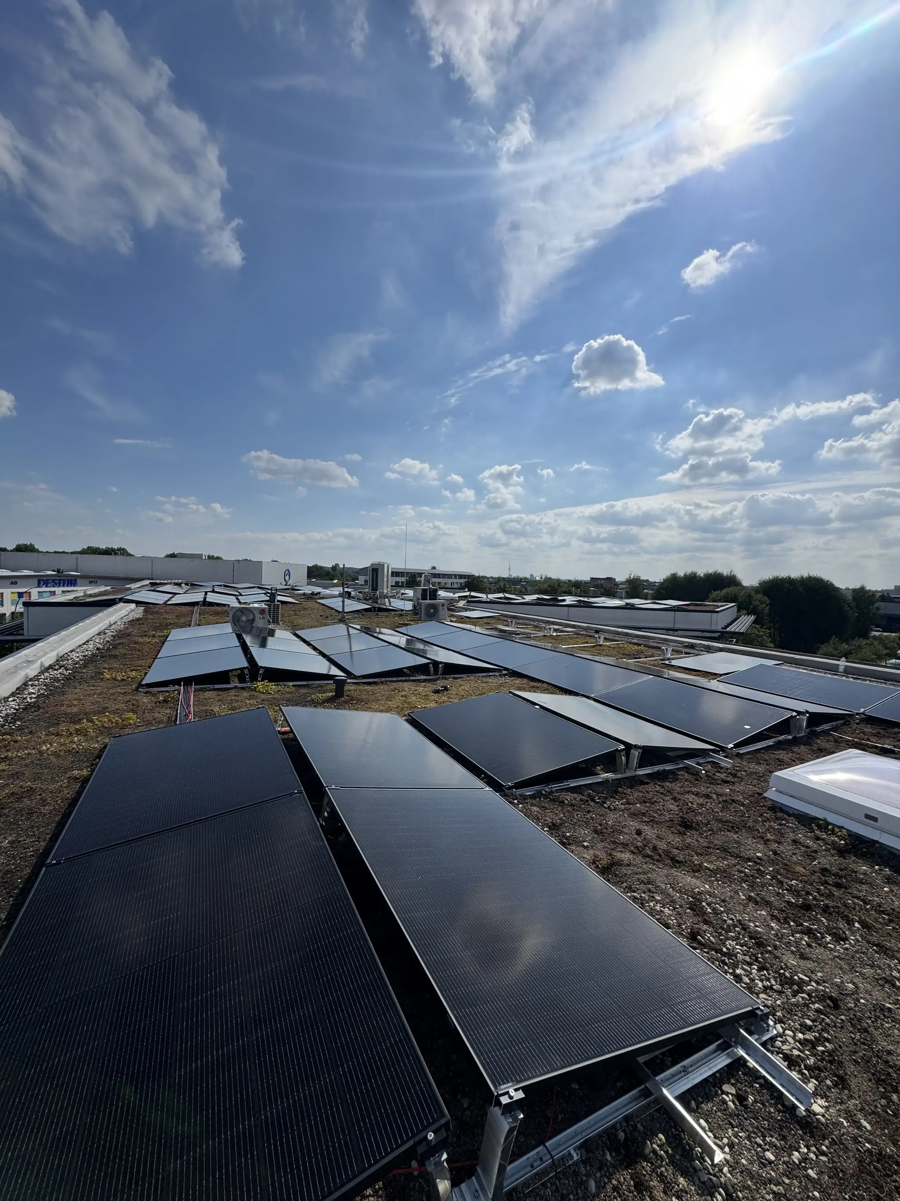 Photovoltaikanlage auf Gewerbe-Flachdach mit schwarzen Solarmodulen auf Aufständerung unter blauem Himmel