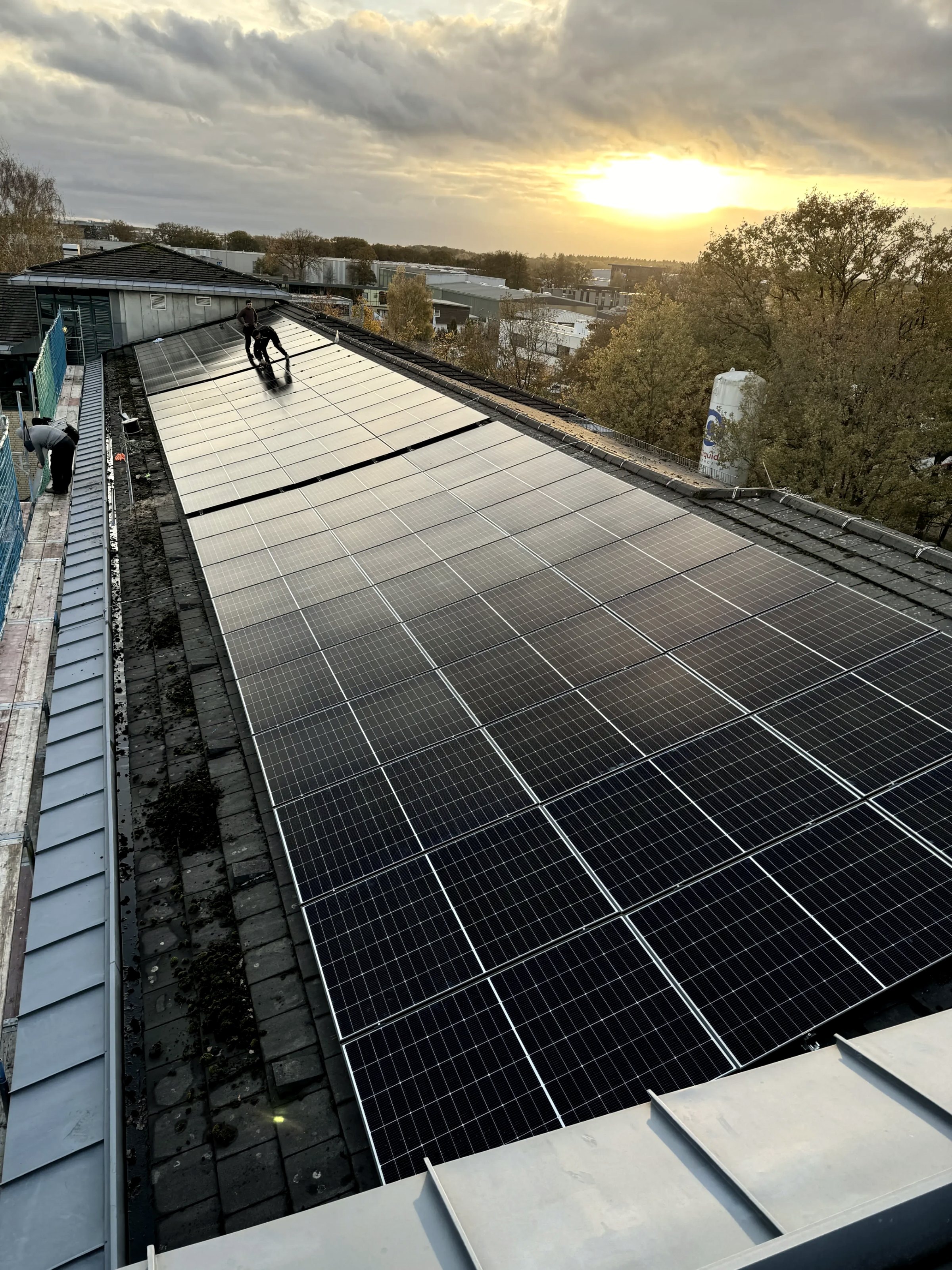 Montage einer Photovoltaikanlage auf einem Gewerbedach bei Sonnenuntergang mit Solarmodulen