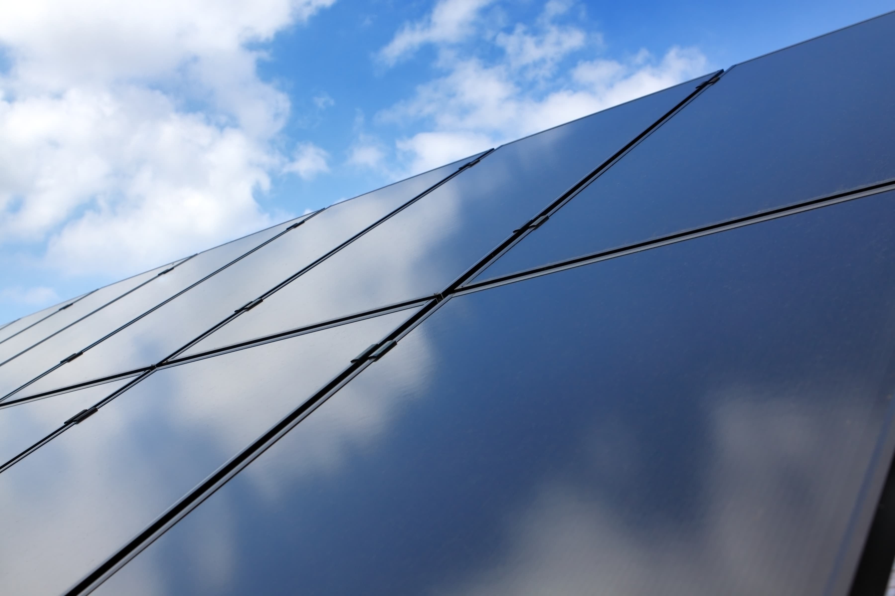 Photovoltaikanlage mit dunklen Solarmodulen vor blauem Himmel zur Stromerzeugung