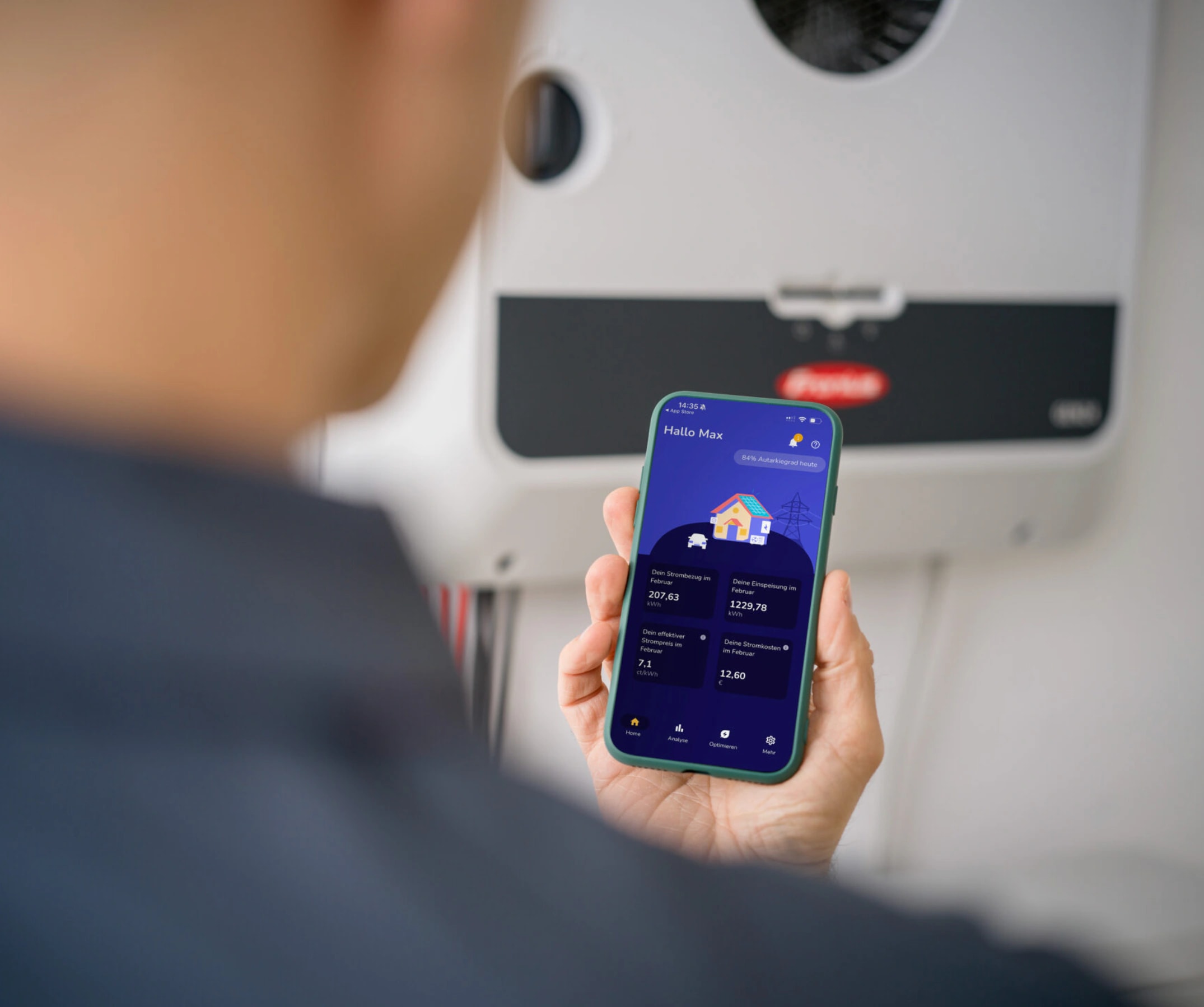 Person prüft PV-App mit Stromverbrauch und Autarkiegrad vor Fronius Wechselrichter